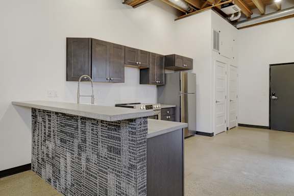 A kitchen with a white counter top and a black and white patterned backsplash.