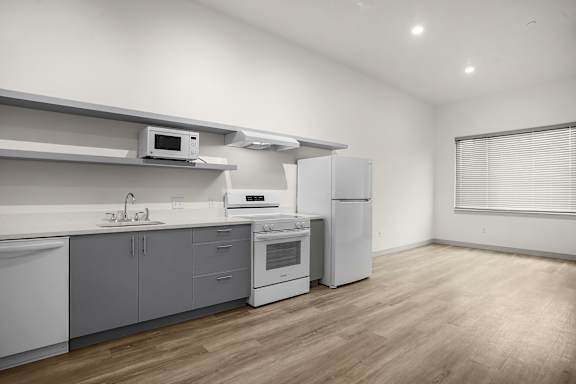 A modern kitchen with white appliances and wooden flooring.
