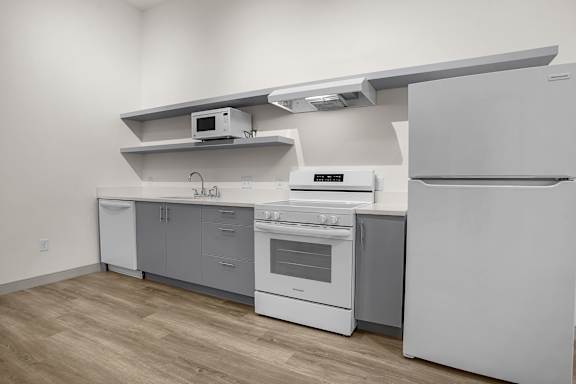 A white kitchen with a refrigerator, oven, and microwave.