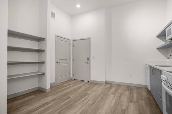 A kitchen with a white wall and a wooden floor.