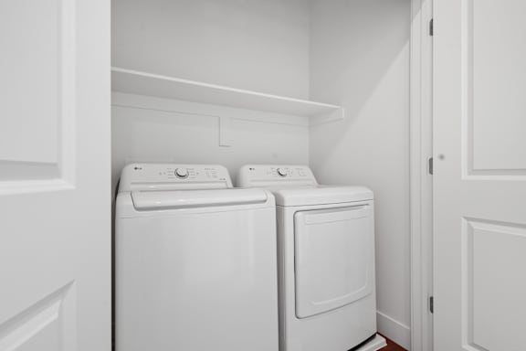 Two white front loading washing machines in a laundry room.