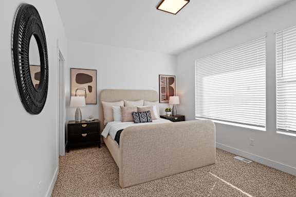 A bedroom with a large bed and a round mirror on the wall.