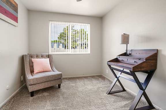 A room with a grey chair and a wooden desk.
