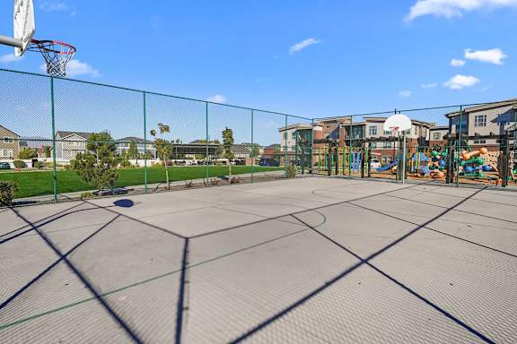 A basketball court with a green fence and a basketball hoop.