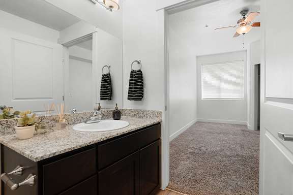 A bathroom with a sink, mirror, and a fan.