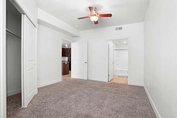 A room with a ceiling fan and carpeted floor.