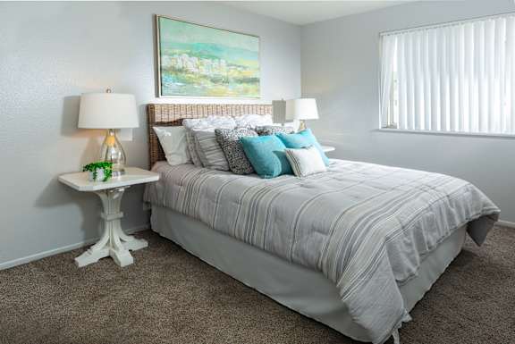 A bedroom with a large bed and two lamps.