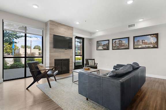 A modern living room with a grey couch, a fireplace, and a chair.