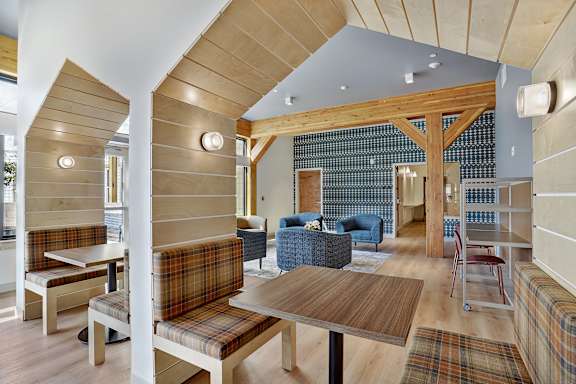 A room with a wooden ceiling and a checkered couch.