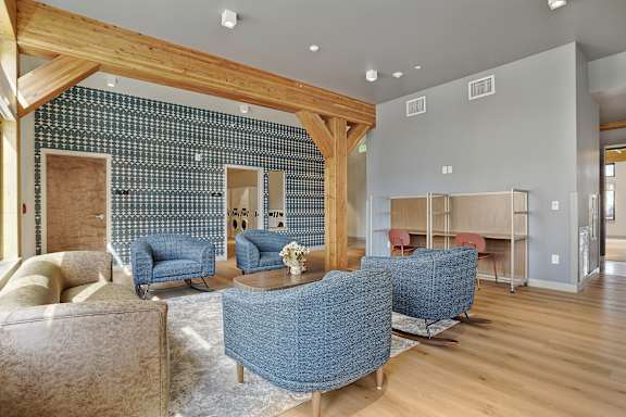 A living room with a blue sofa and a wooden beam ceiling.