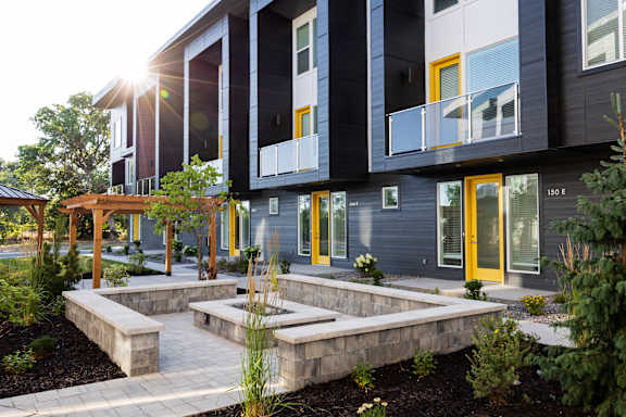 A modern building with a balcony and a garden in front.
