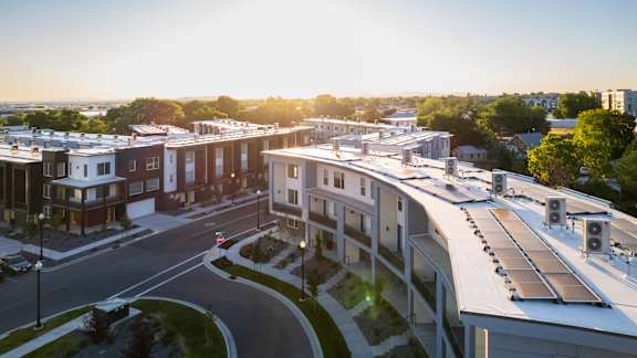A sunny day in a residential area with apartment buildings and solar panels on the roofs.