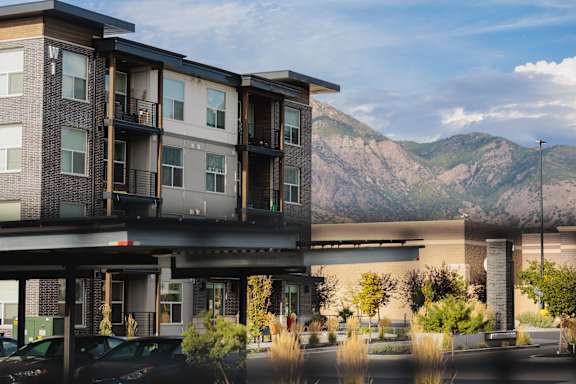 A modern apartment building with a mountain in the background.