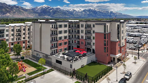 A large building with a red awning in front of a mountain range.
