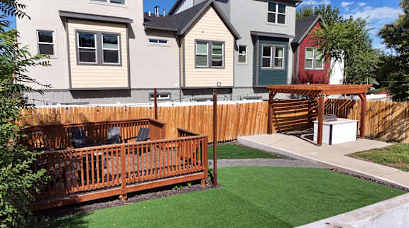 A backyard with a wooden deck and a green lawn.