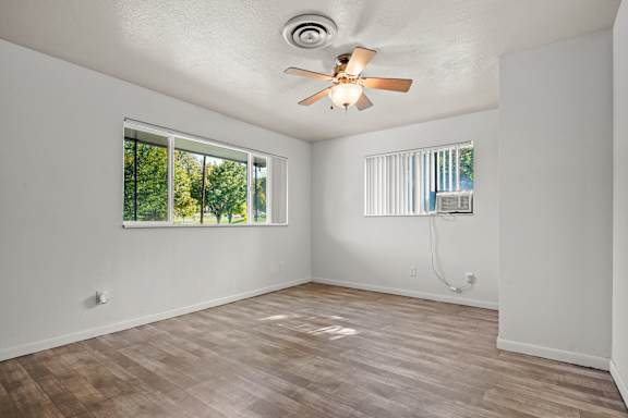 A room with a ceiling fan and wooden flooring.