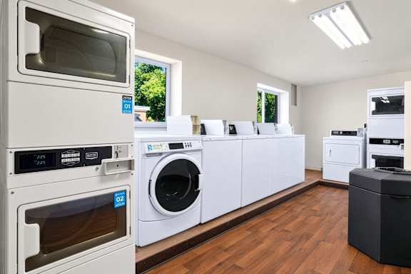 A row of white appliances in a room with wooden floors.