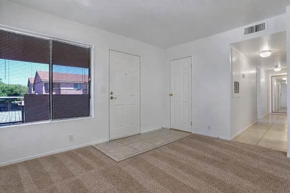 A room with white walls and a carpeted floor with three white doors.