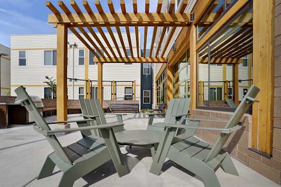 A wooden pergola with green chairs and a table in the foreground.