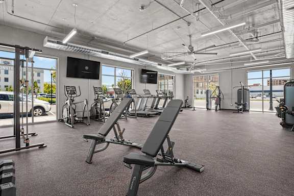 A gym with a row of treadmills and a television mounted on the wall.