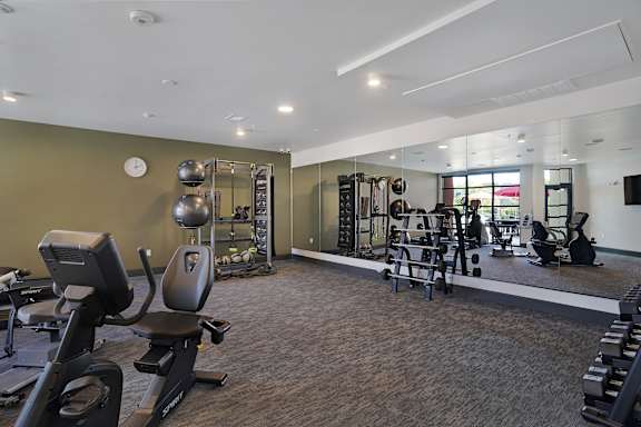 A gym with a variety of equipment including treadmills, weights, and exercise machines.