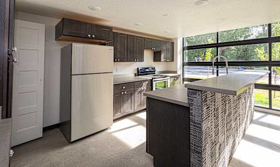 A modern kitchen with a large island and a view of the street outside.