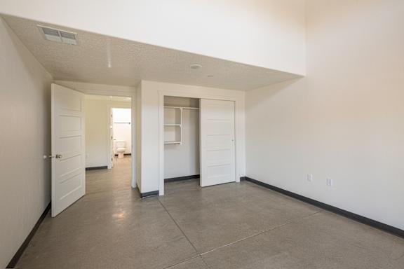 A large empty room with white walls and a grey floor.