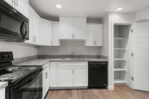 A kitchen with white cabinets and black appliances.