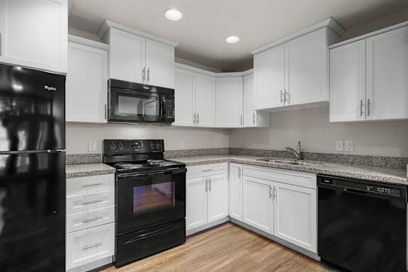 A black stove and oven in a kitchen with white cabinets.