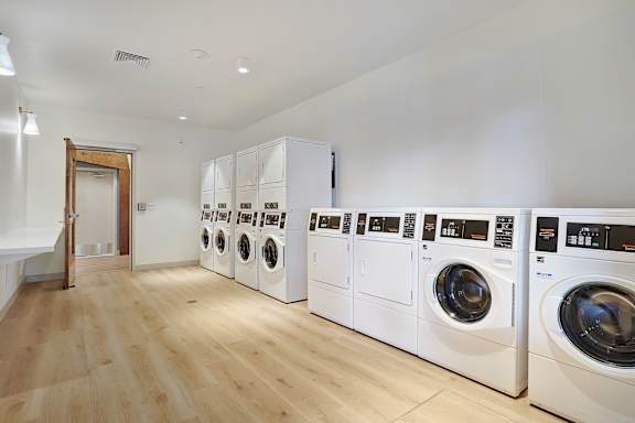 A row of white front load washing machines in a laundry room.