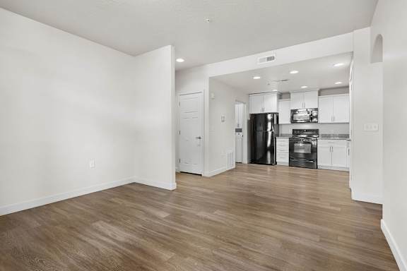 A kitchen with white cabinets and a black fridge.