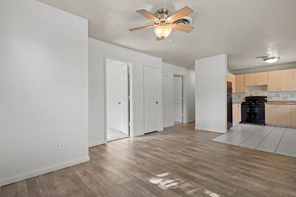 A room with a ceiling fan and wooden flooring.