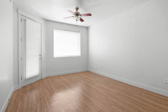 A room with a ceiling fan and a window with blinds.