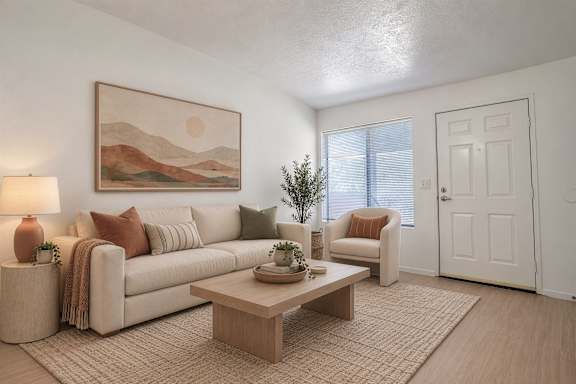 A living room with a couch, a coffee table, and a painting on the wall.