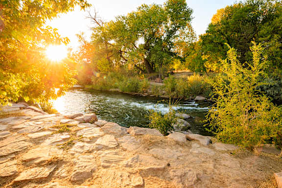 A river flows through a rocky landscape with trees on the banks.