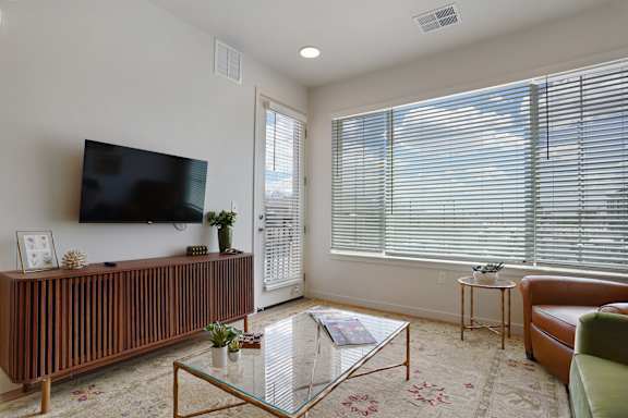 A living room with a flat screen TV mounted on the wall above a wooden cabinet.