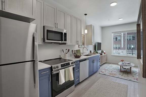A modern kitchen with a refrigerator, microwave, oven, and sink.