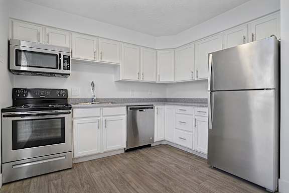 A kitchen with a stainless steel refrigerator, oven, and microwave.