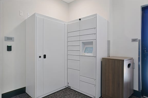 A white storage unit with a door open and a trash can to the side.