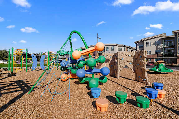 A playground with a green swing set and a blue ball.