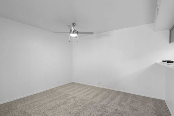 A room with a ceiling fan and carpeted floor.