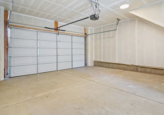 A large, empty garage with a white door and a concrete floor.