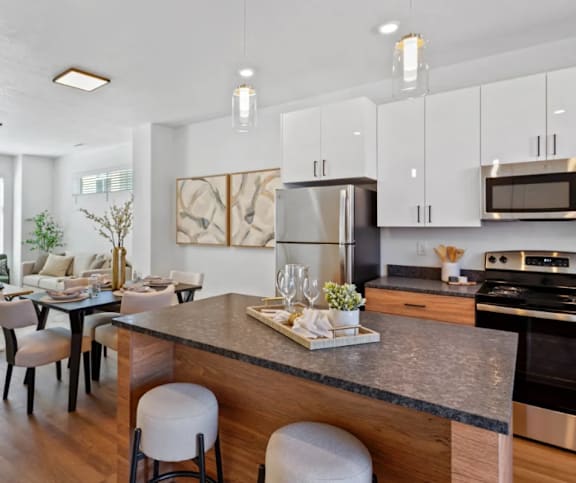 A modern kitchen with a dark granite countertop and white cabinets.