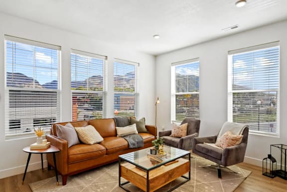 A living room with a brown couch, a glass coffee table, and a chair.