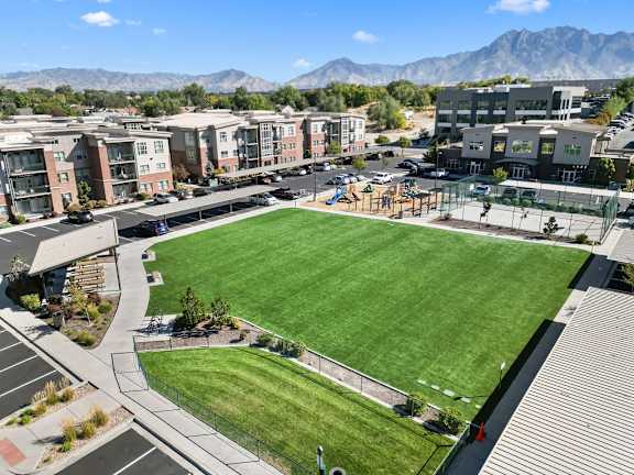 A large grassy field is surrounded by apartment buildings.
