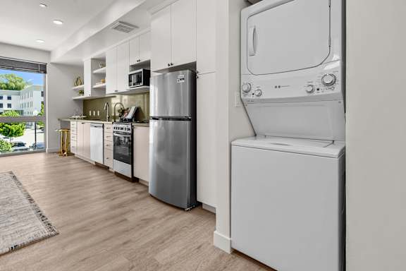 A modern kitchen with a refrigerator, oven, and washing machine.