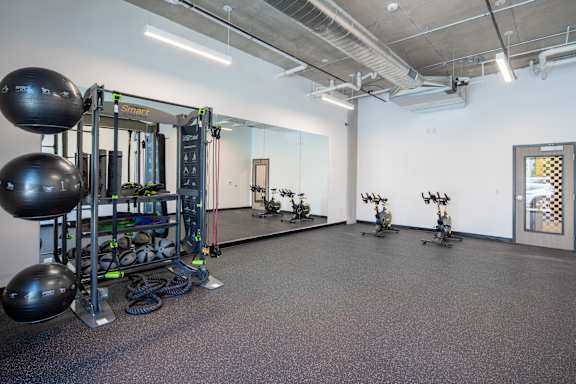 A gym with a variety of equipment including a squat rack, kettlebells, and a mirror.