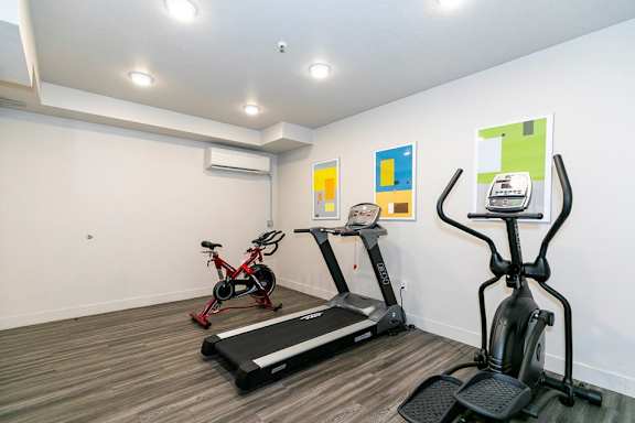 A room with a treadmill, exercise bike, and elliptical trainer.