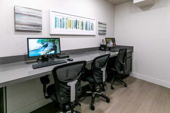 A white desk with a computer and two chairs.