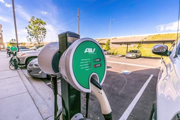 A green and white electric vehicle charging station with a sign that says AV CHARGE.